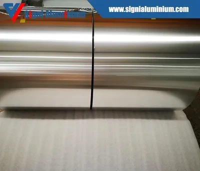 Two wide aluminium foil jumbo rolls side by side on a padded surface
