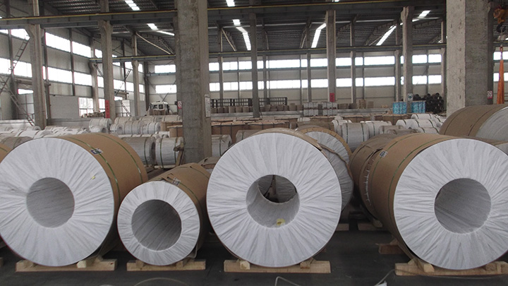 Rows of paper-wrapped aluminium coils on wooden pallets in a warehouse