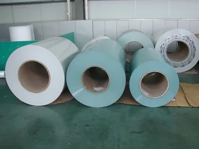 Several prepainted coils in white and pale green standing in a workshop