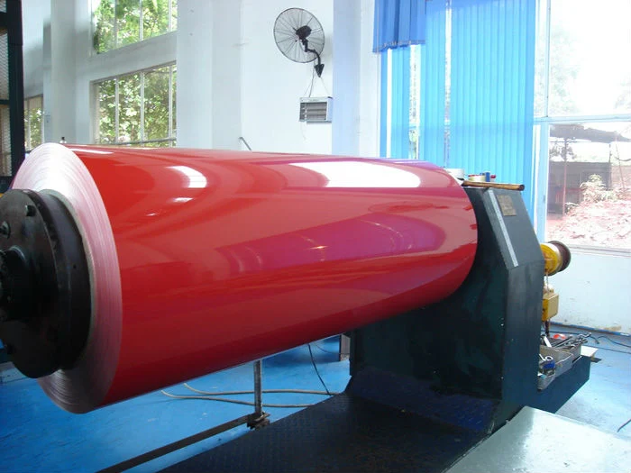 A glossy red color coated coil mounted on a winder in a coating workshop