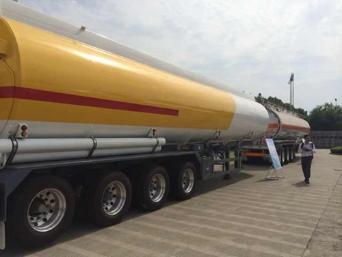 A yellow and white aluminium road tanker parked on a concrete apron